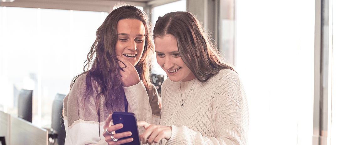 Two Howdy team members collaborating while looking at a phone together